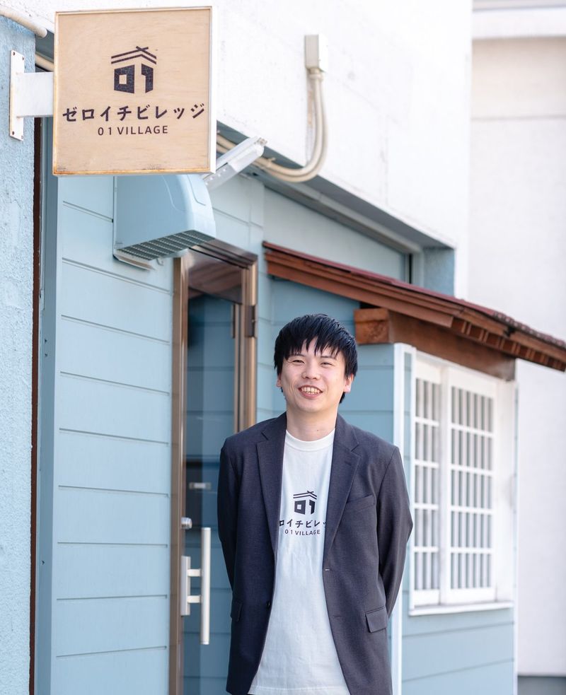 ゼロイチビレッジの看板の前に立つ碇谷